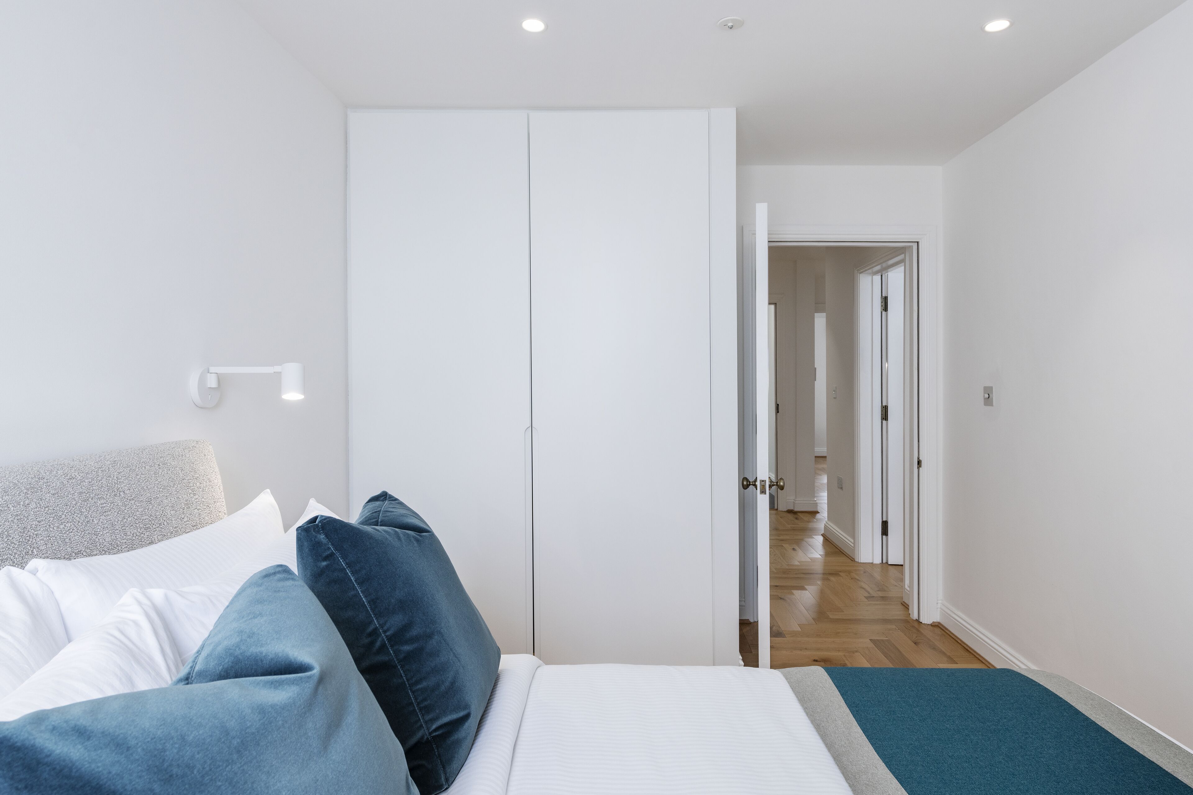 Une chambre à coucher comprenant un lit, une armoire et une porte donnant sur un couloir.
