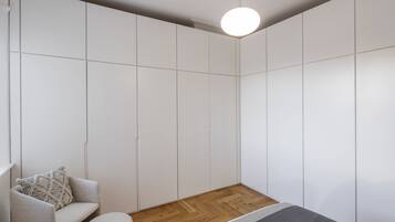 A modern room with a built-in wardrobe, a round light fixture, a wooden floor, and a grey sofa with a patterned pillow.