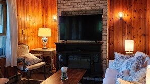 Una sala de estar acogedora con chimenea de ladrillo, televisor de pantalla plana, muebles de madera y un espacio de descanso confortable.
