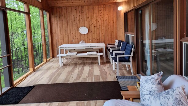 Una cabaña de madera con comedor, sofá y ventanas amplias.