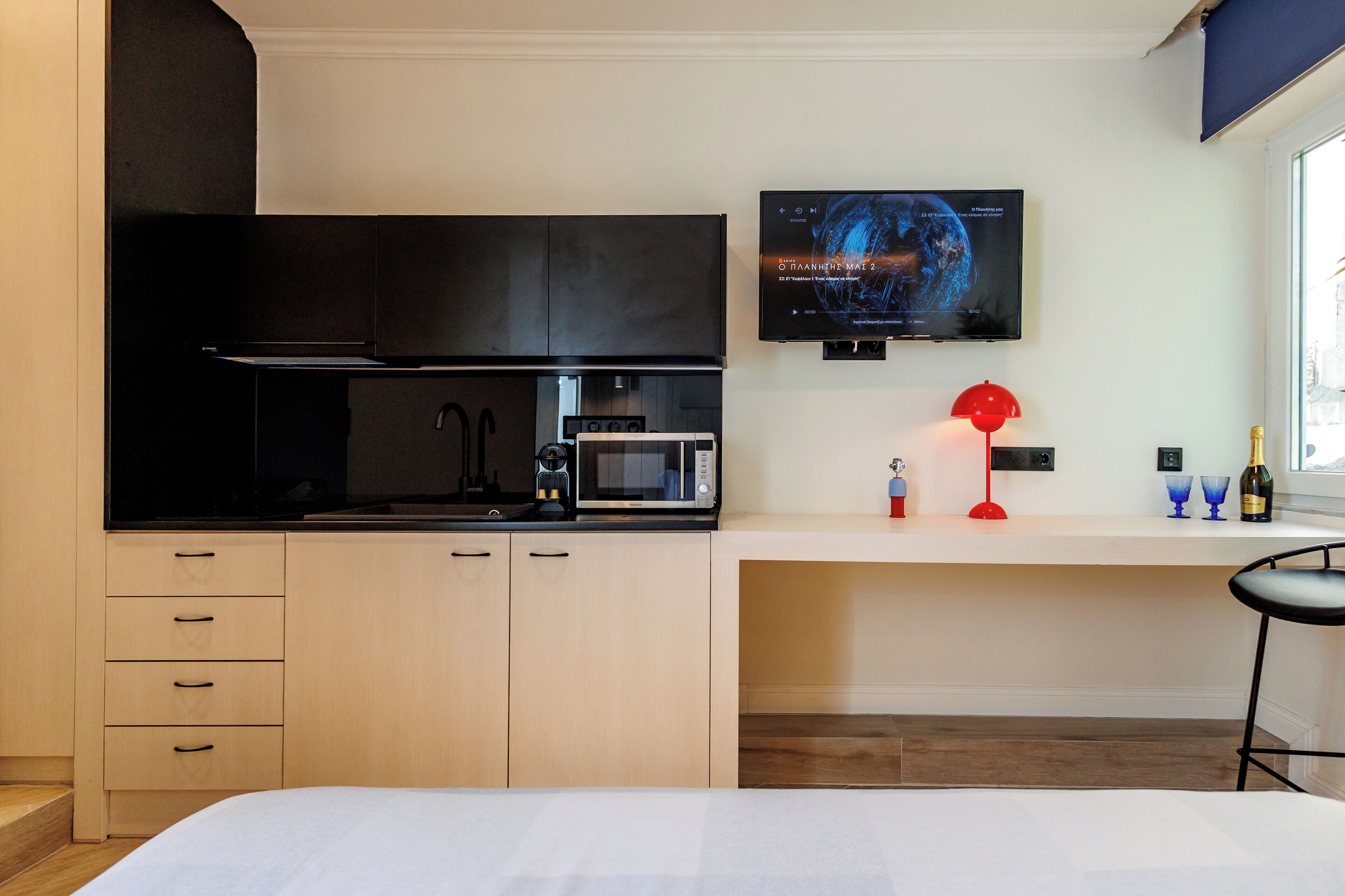 A modern kitchen with a flat-screen TV above it, a microwave, and a coffee maker.