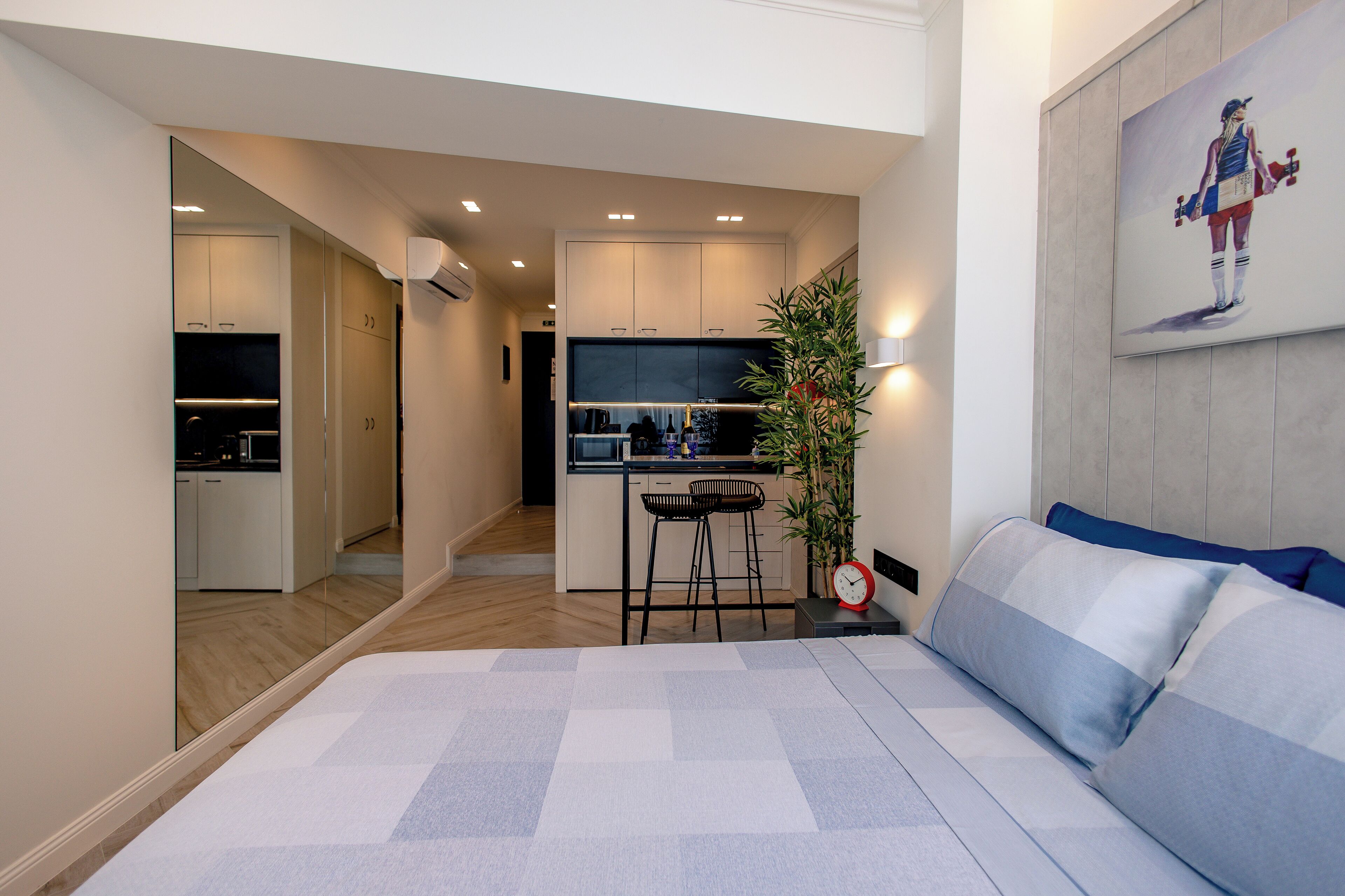 A modern hotel room with a large bed, a small kitchenette, and a dining area.
