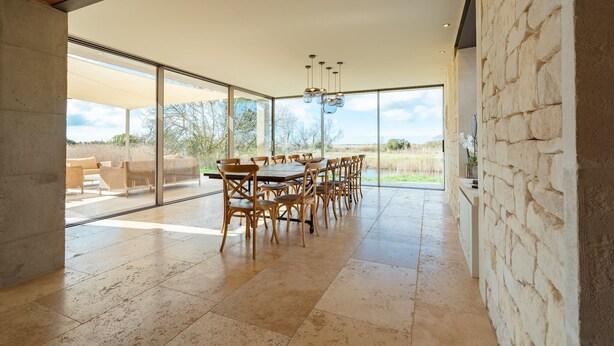 A spacious dining area with a large table and chairs, large windows, and a view of the outdoors. - Mas du Couvin - maison d'hôtes Camargue (Saintes-Maries-de-la-Mer)