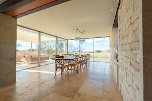 Un comedor amplio con una mesa grande y sillas, ventanas grandes y vistas al exterior.
