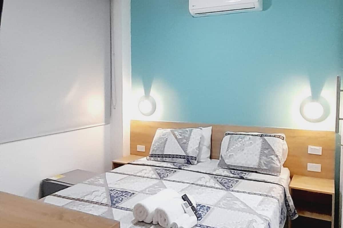 Ein Schlafzimmer mit einem Bett, Nachttischen, einem Schreibtisch und einer Klimaanlage.
