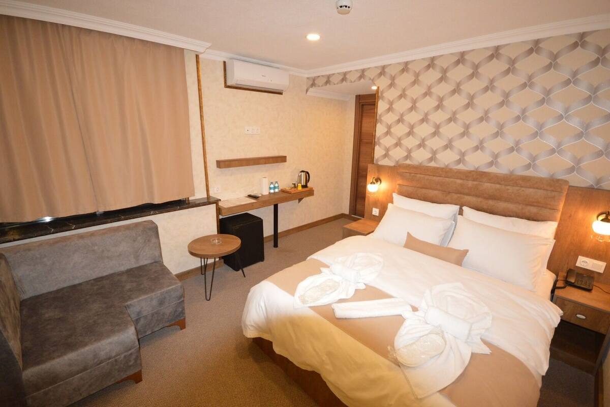 A hotel room with a bed, a desk, a chair, and a small table.