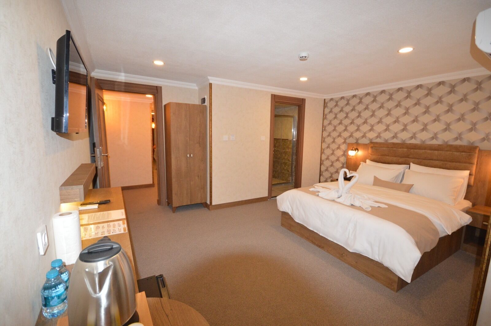 A hotel room with a bed, a desk, a television, a wardrobe, and a bathroom.
