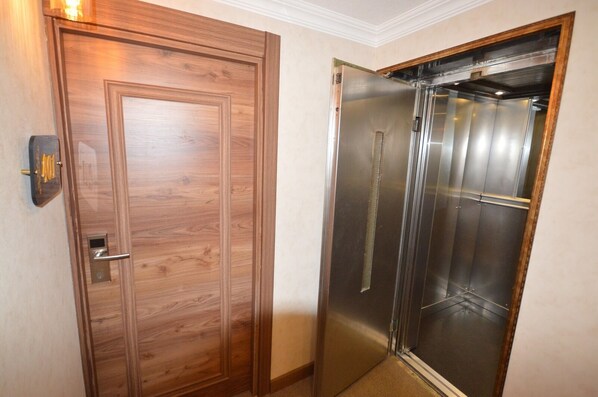 A wooden door with a modern elevator adjacent to it.