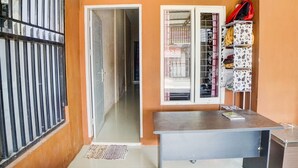 A room with a desk, a wardrobe, and a window with a metal grill. - Hotel O Penginapan Syariah Faster Inn (Medan)