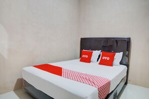 A hotel room with a bed, white and red bedding, and two red pillows with the word "OYO" on them. - Hotel O Penginapan Syariah Faster Inn (Medan)