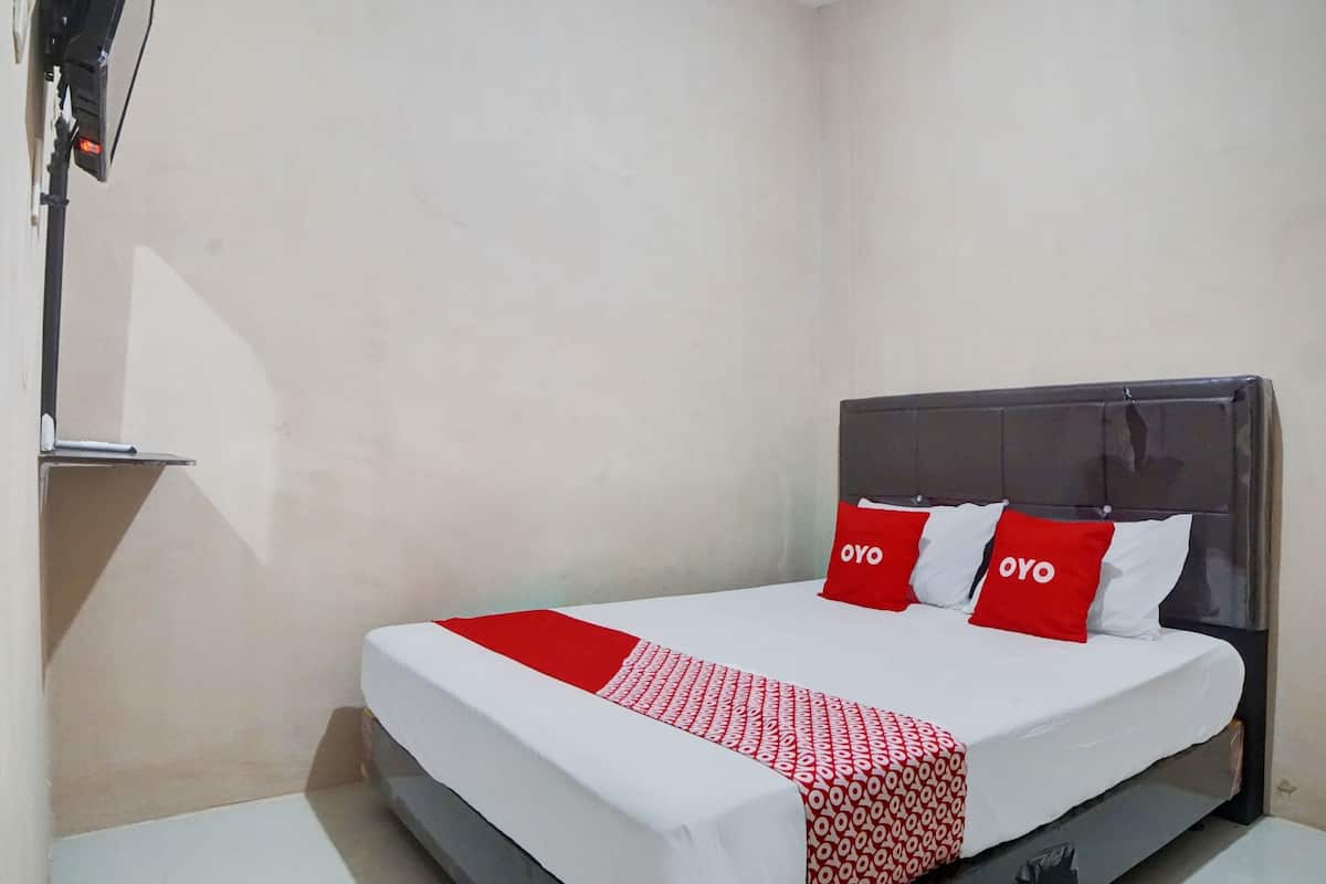 A hotel room with a bed, a bedside table, and a wall-mounted TV.