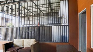 A room with a sofa, a table, and a window with metal bars. - Hotel O Penginapan Syariah Faster Inn (Medan)