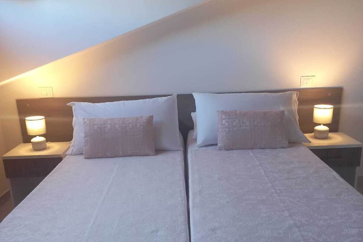 A twin bed room with two bedside tables, each with a lamp.
