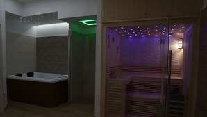 Um banheiro moderno com uma banheira livre, uma sauna em vidro e um lavatório de madeira.