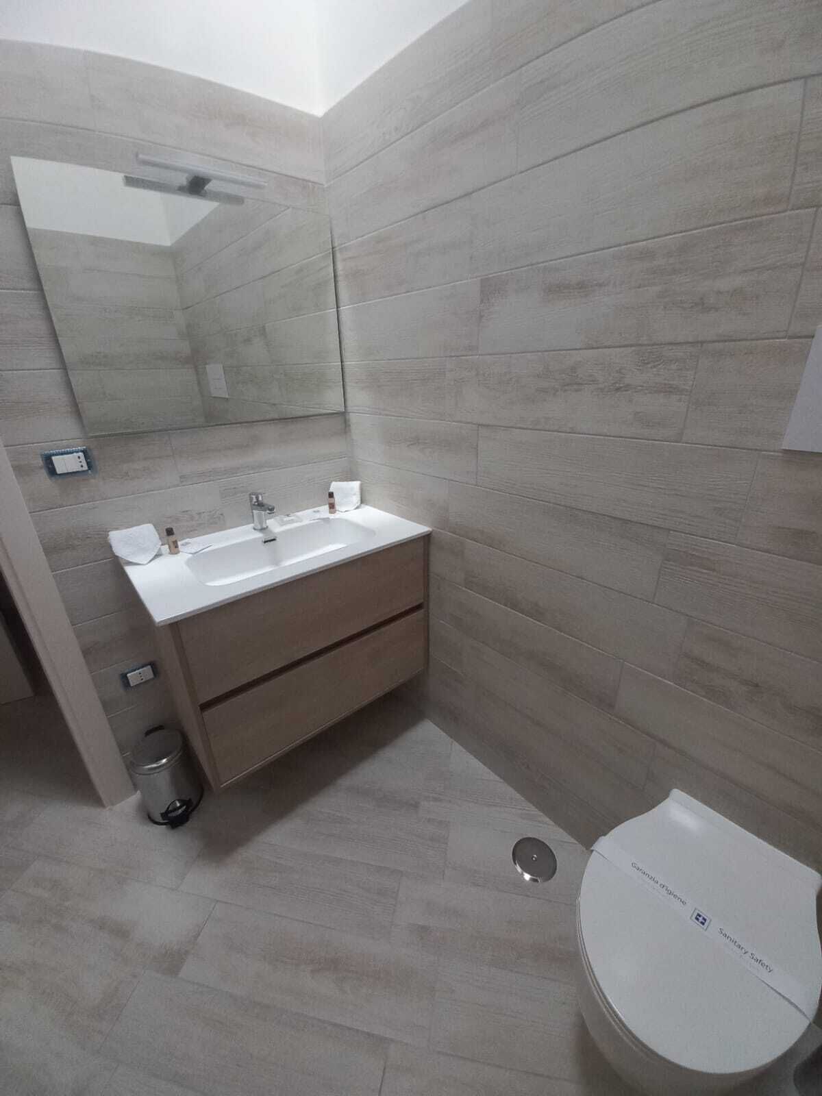 Une salle de bain avec un lavabo blanc, un miroir et des toilettes.