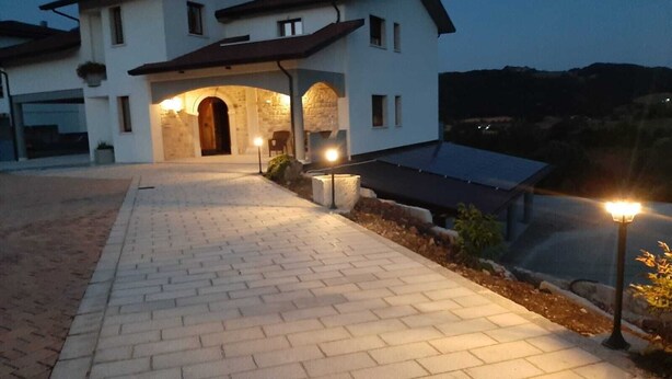 Uma casa de dois andares com um caminho de paralelepípedos que leva a uma entrada em arco de pedra.