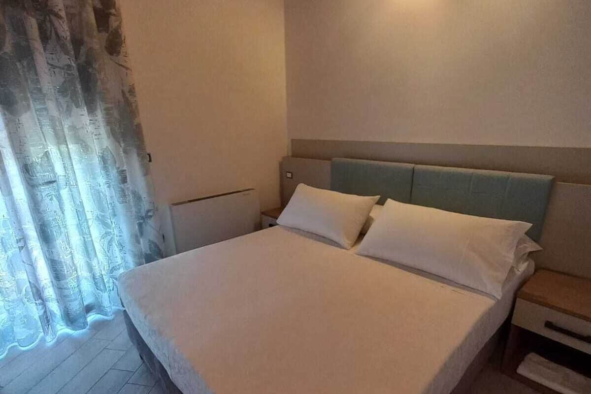 A bedroom with a large bed, a nightstand, a headboard, and a ceiling light fixture.