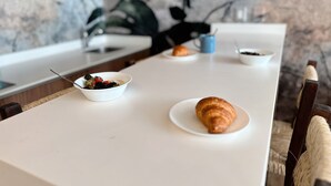 A kitchen counter with a bowl of fruit, a croissant, and a coffee cup. - Alterhome Amour 307 (Tulum)