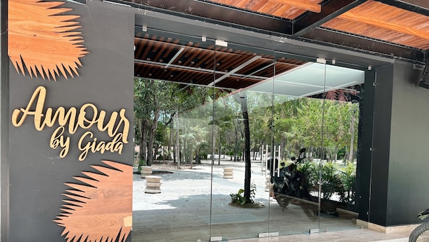A modern entrance with a glass door, a wooden sun design, and the text "Amour by Giada". - Alterhome Amour 307 (Tulum)