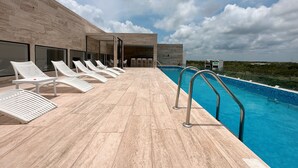 A rooftop pool area with lounge chairs and a clear view of the surrounding landscape. - Alterhome Amour 307 (Tulum)
