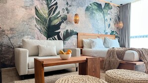 A modern living room with a sofa, a coffee table with fruit, and woven ottomans. - Alterhome Amour 307 (Tulum)