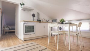 A modern kitchen with white cabinetry, a built-in oven, a microwave, and a dining area with a table and chairs. - SandybeachApartment2 in the Golden Island  (Vila Baleira)