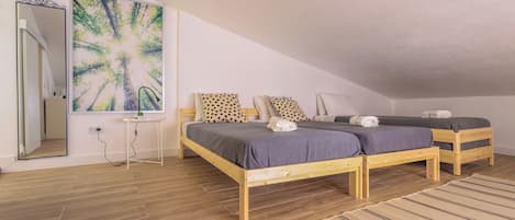 A bedroom with two wooden beds, a large mirror, and a painting of trees.