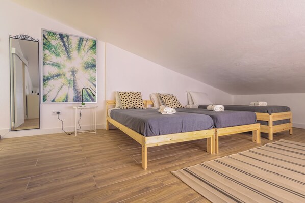 A bedroom with two wooden beds, a large mirror, and a painting of trees. - SandybeachApartment2 in the Golden Island (Vila Baleira)