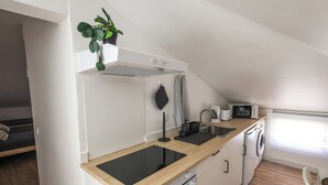 A compact kitchen with a wooden countertop, a built-in microwave, a washing machine, and a small window. - SandybeachApartment2 in the Golden Island  (Vila Baleira)