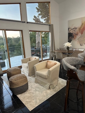 A spacious living room with large windows, a dining area, and a view of the outdoors.
