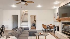 A modern living room with a sectional sofa, a round coffee table, and a fireplace. - Spacious Lake Hamilton House with Pool and Hot Tub! (Hot Springs)