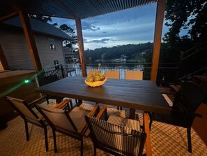 An outdoor dining area with a table and chairs, overlooking a body of water and a dock. - Spacious Lake Hamilton House with Pool and Hot Tub! (Hot Springs)