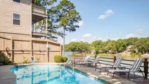 A swimming pool with lounge chairs, a wooden deck, and a view of a lake and trees. - Spacious Lake Hamilton House with Pool and Hot Tub! (Hot Springs)