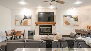 A modern living room with a fireplace, a television, and abstract art on the walls. - Spacious Lake Hamilton House with Pool and Hot Tub! (Hot Springs)