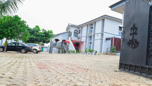 A paved driveway leading to a building with a staircase and a covered entrance. - Cozy Suites (Akure)