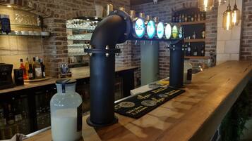 A bar with a brick wall, a beer tap system, and a wooden counter.