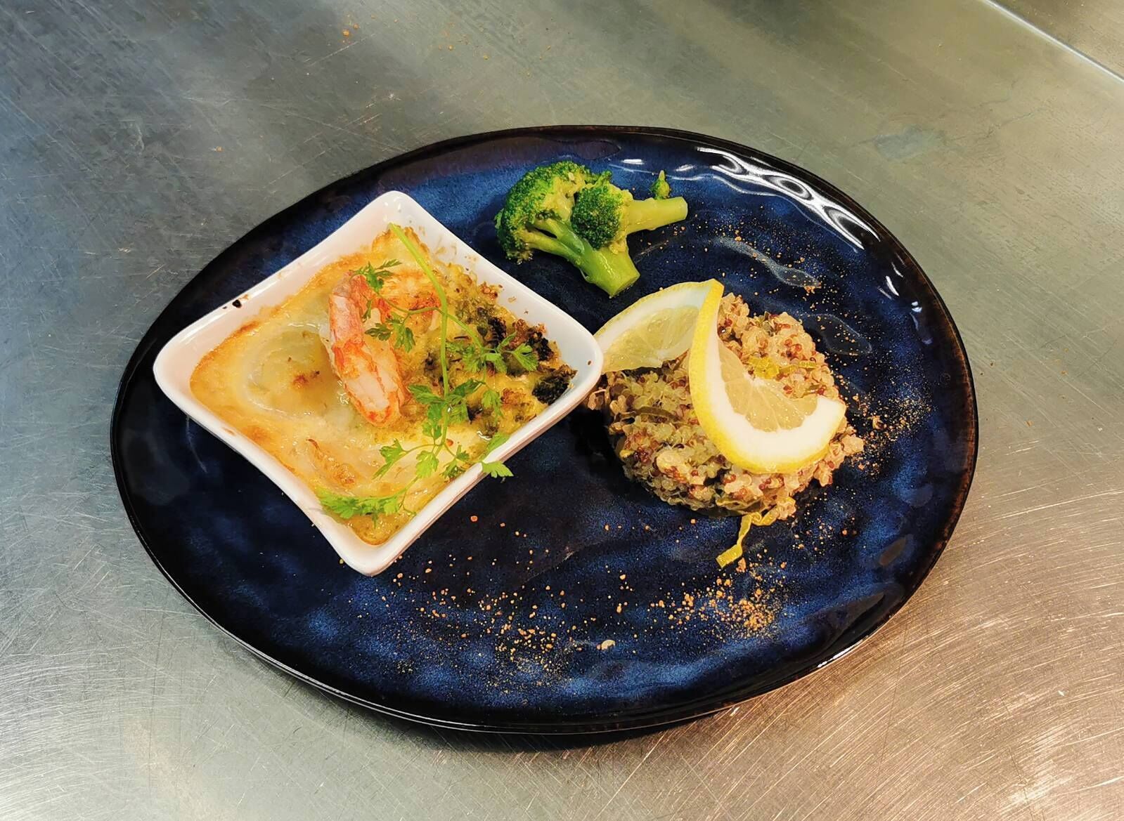 A plate with a seafood dish, a vegetable dish, and a lemon wedge.