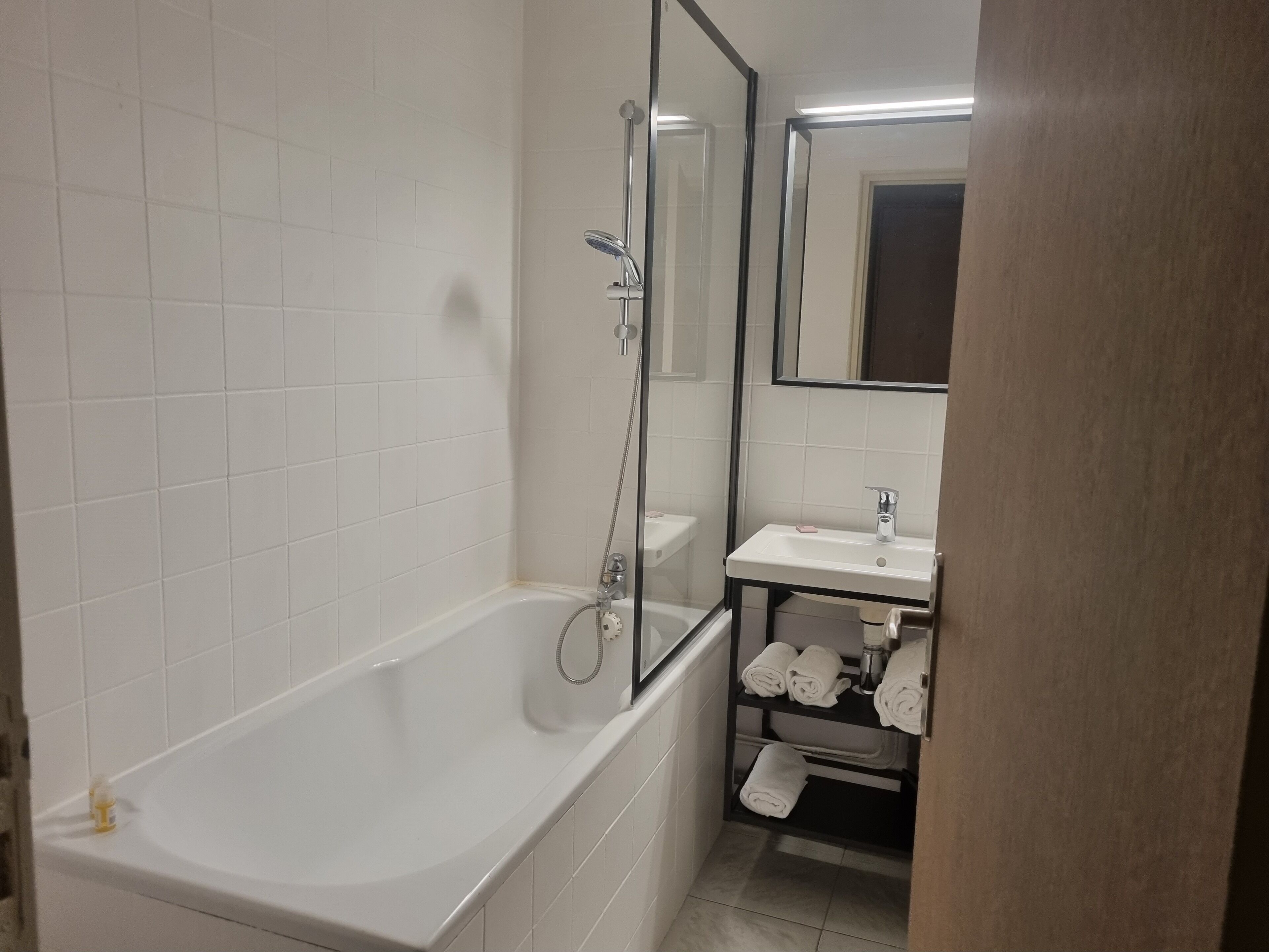 Une salle de bain avec une baignoire blanche, un lavabo et un miroir.