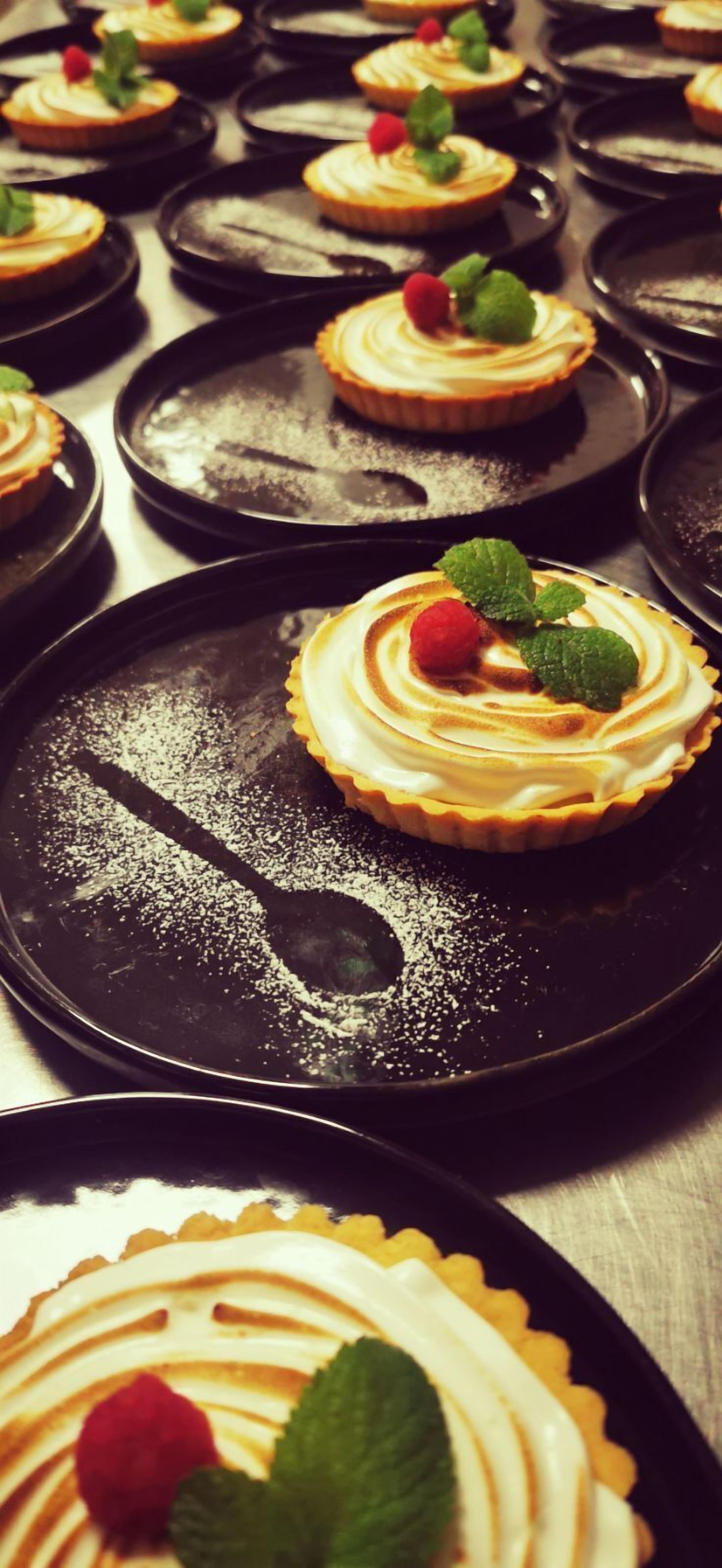 A series of dessert plates with whipped cream and mint leaves, arranged on a table.