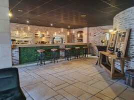 Un área de bar con pared de ladrillo, césped artificial verde y taburetes de madera.