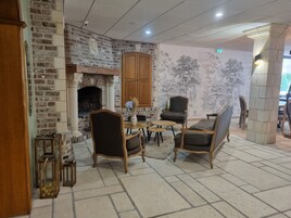 Un interior acogedor con chimenea de ladrillo, muebles de madera y un mural de árboles.
