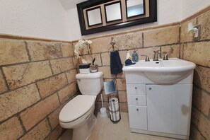 A bathroom with a toilet, sink, and tiled walls. - Chic Ocean Miami 88 (Cutler Bay)
