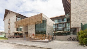 A modern building with a stone facade, large windows, and outdoor seating areas. - Sunny Hall Flat by EasyHome (Ipojuca)