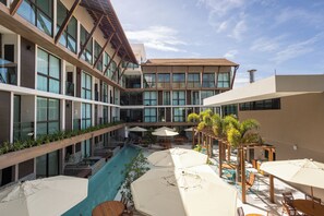 Un hôtel moderne doté d’une piscine centrale, d’un espace extérieur aménagé et d’un bâtiment à plusieurs étages avec de grandes fenêtres.