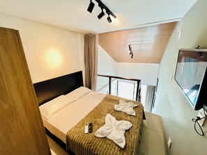 Une chambre d’hôtel avec un lit, une table de chevet, une télévision et un balcon doté d’une rambarde.