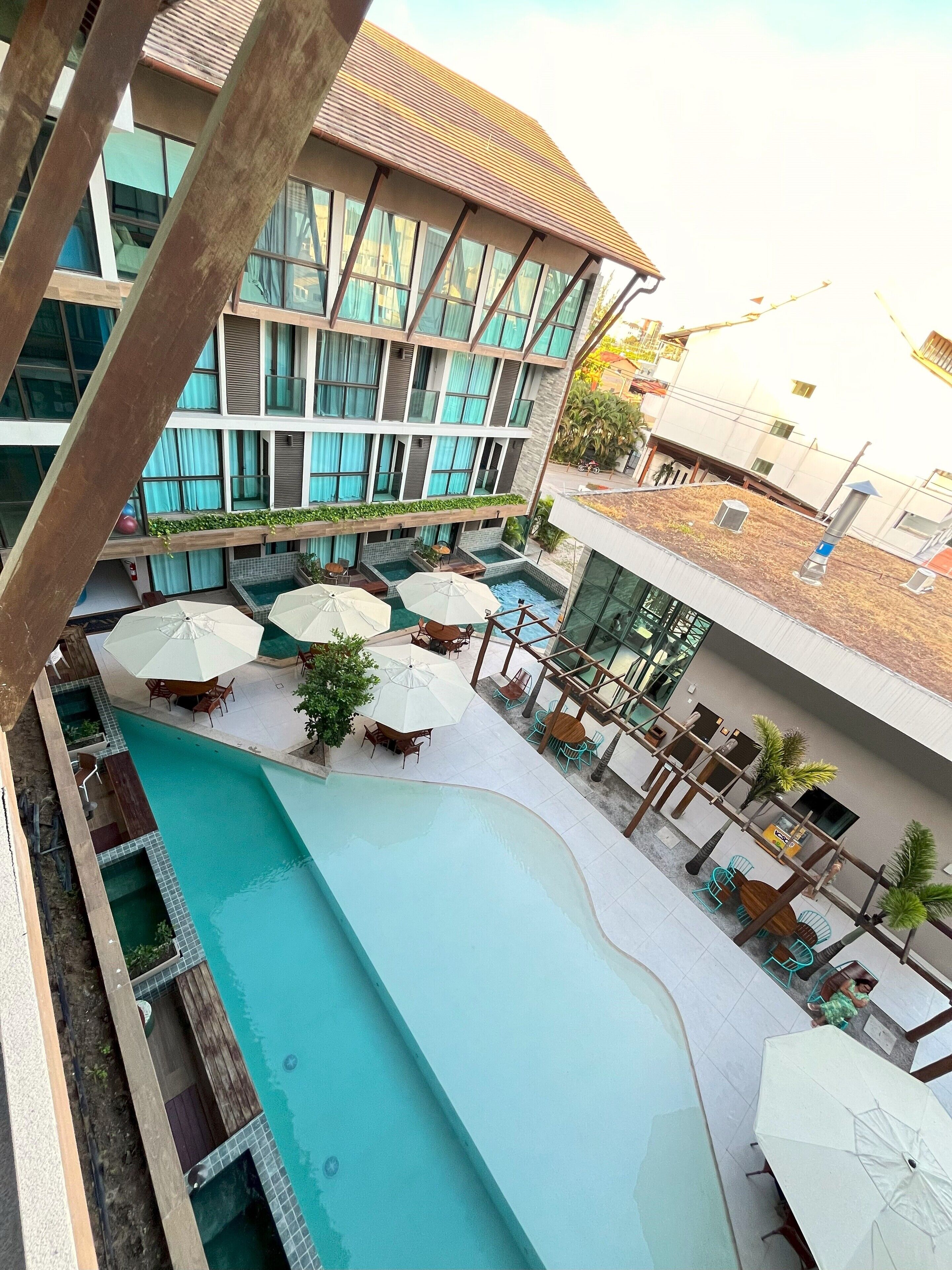 Un hôtel doté d’une piscine sur le toit, d’un espace extérieur aménagé et d’un grand bâtiment avec de nombreuses fenêtres.
