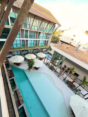 Un hôtel doté d’une piscine sur le toit, d’un espace extérieur aménagé et d’un grand bâtiment avec de nombreuses fenêtres.