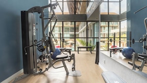 A gym with exercise equipment, large windows, and a view of buildings outside. - Sunny Hall Flat by EasyHome (Ipojuca)
