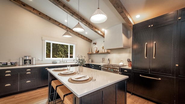 A modern kitchen with a central island, dark cabinetry, and pendant lighting.