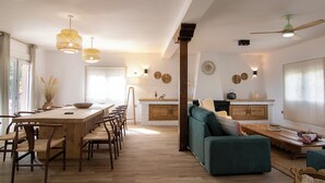 A spacious living area with a wooden dining table, multiple chairs, a teal sofa, and a wooden coffee table. - Casa Rural La Lagunilla Golf (Candeleda)